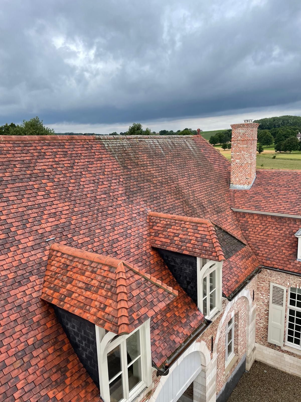 Dak van een villa tijdens professionele dakreiniging door DTRenovatie, links nog met mos, rechts al gereinigd